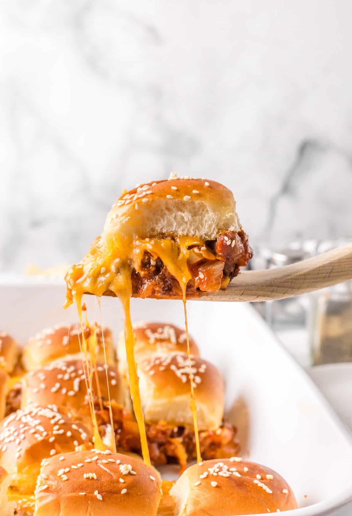 A cheesy sloppy joe slider being served.