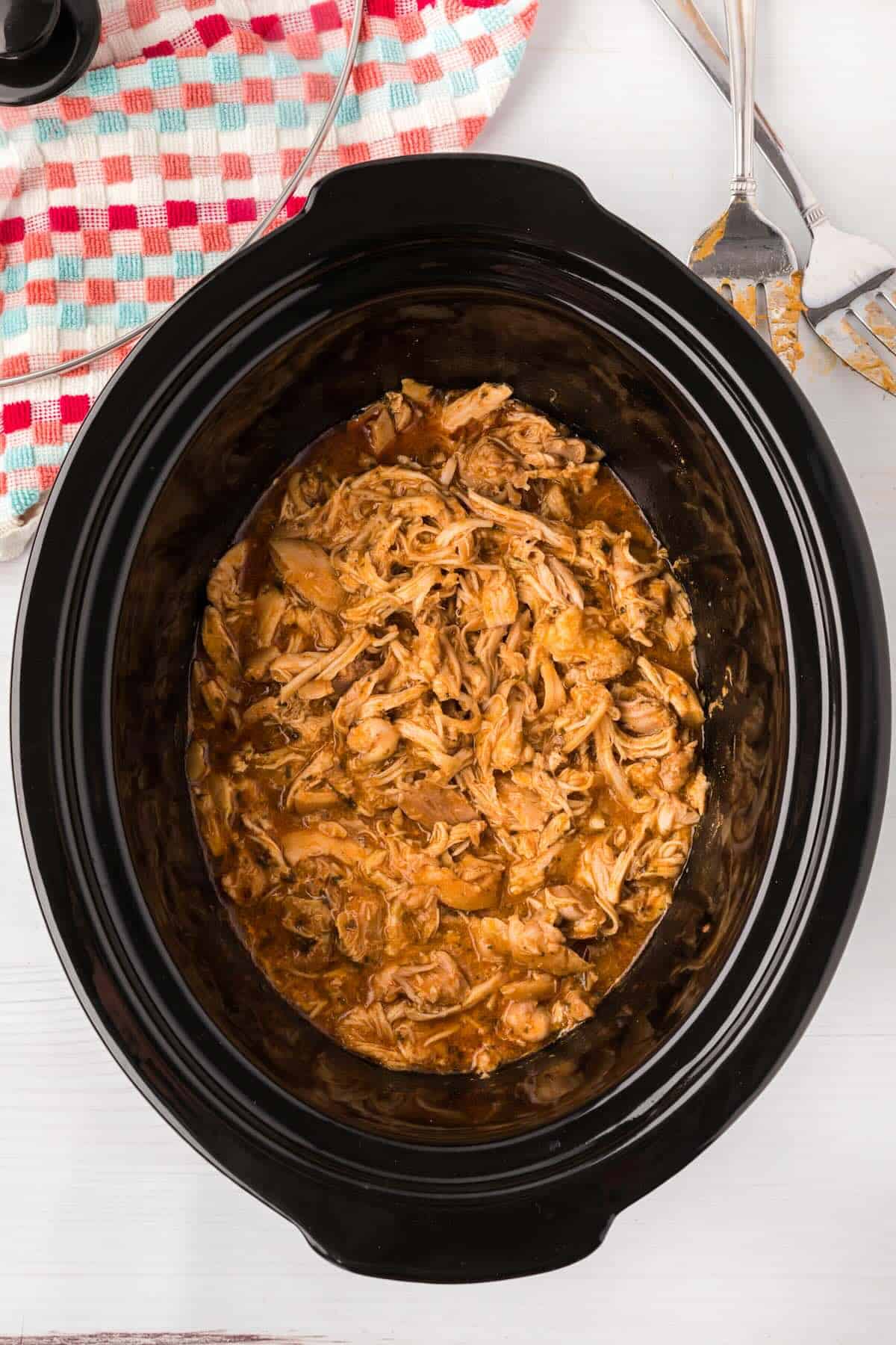 Shredded chicken stirred back into seasoned juices in the slow cooker.