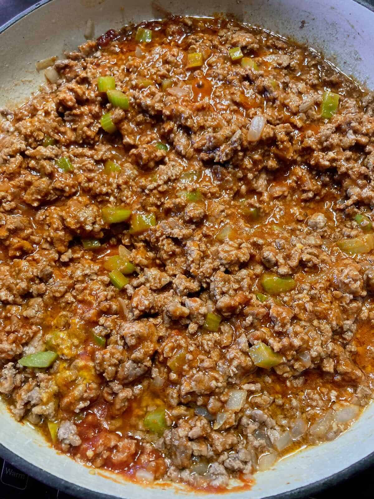 Sloppy joe meat mixture simmering in a skillet with tangy sauce.