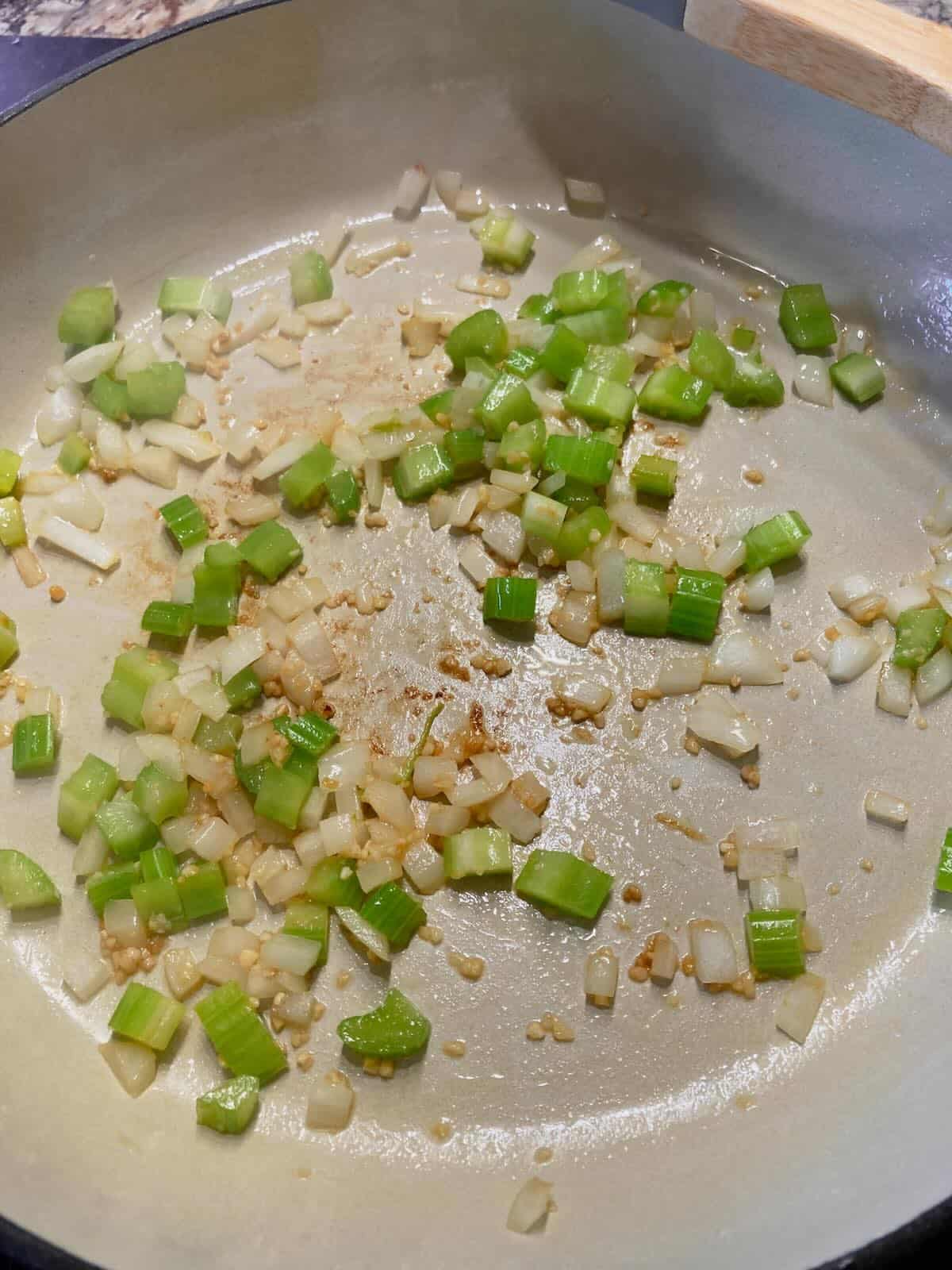 Onions, garlic, and celery cooking in a skillet for homemade sloppy joes.