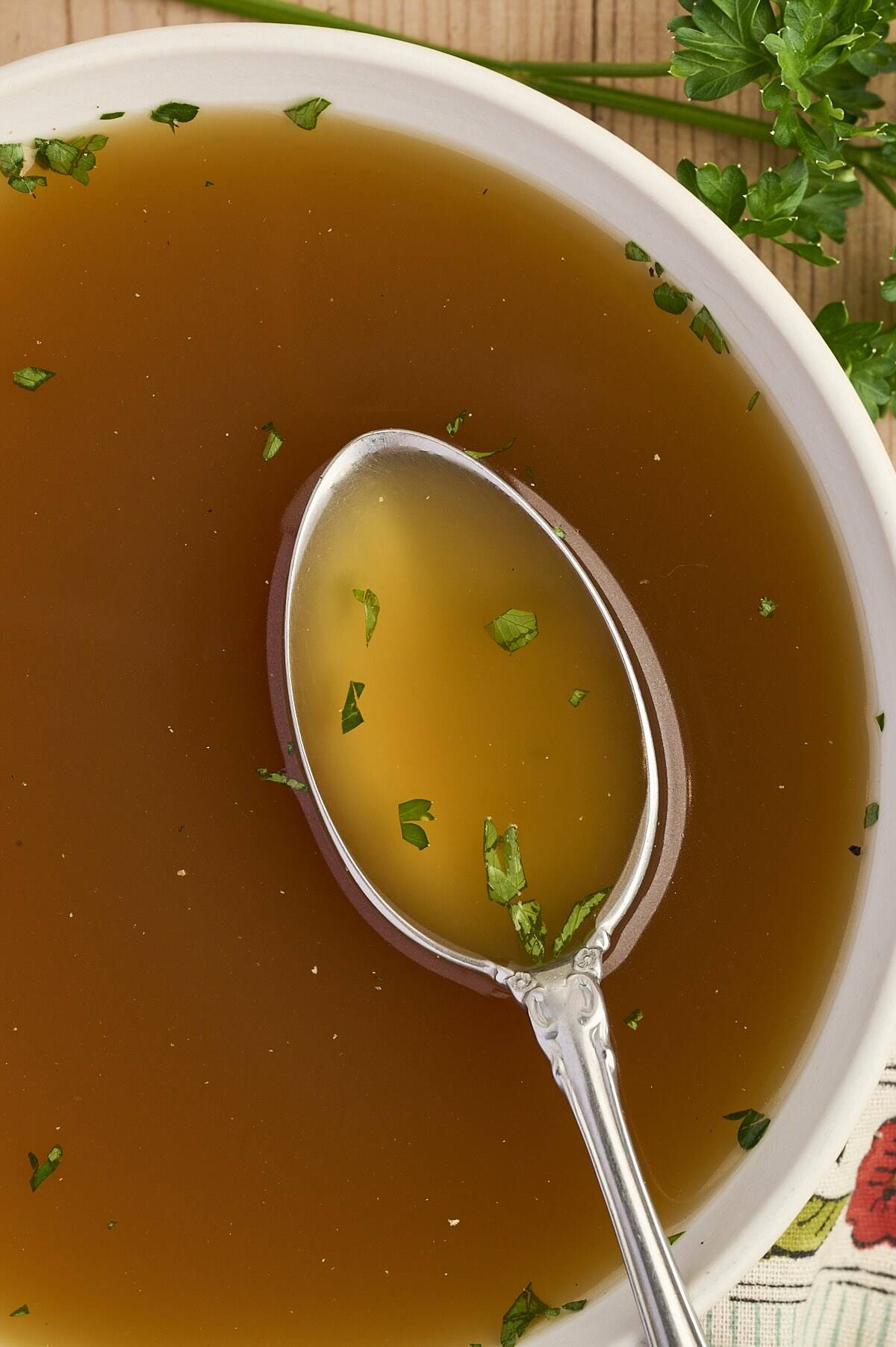 A spoonful of homemade chicken broth made in the slow cooker with fresh parsley.