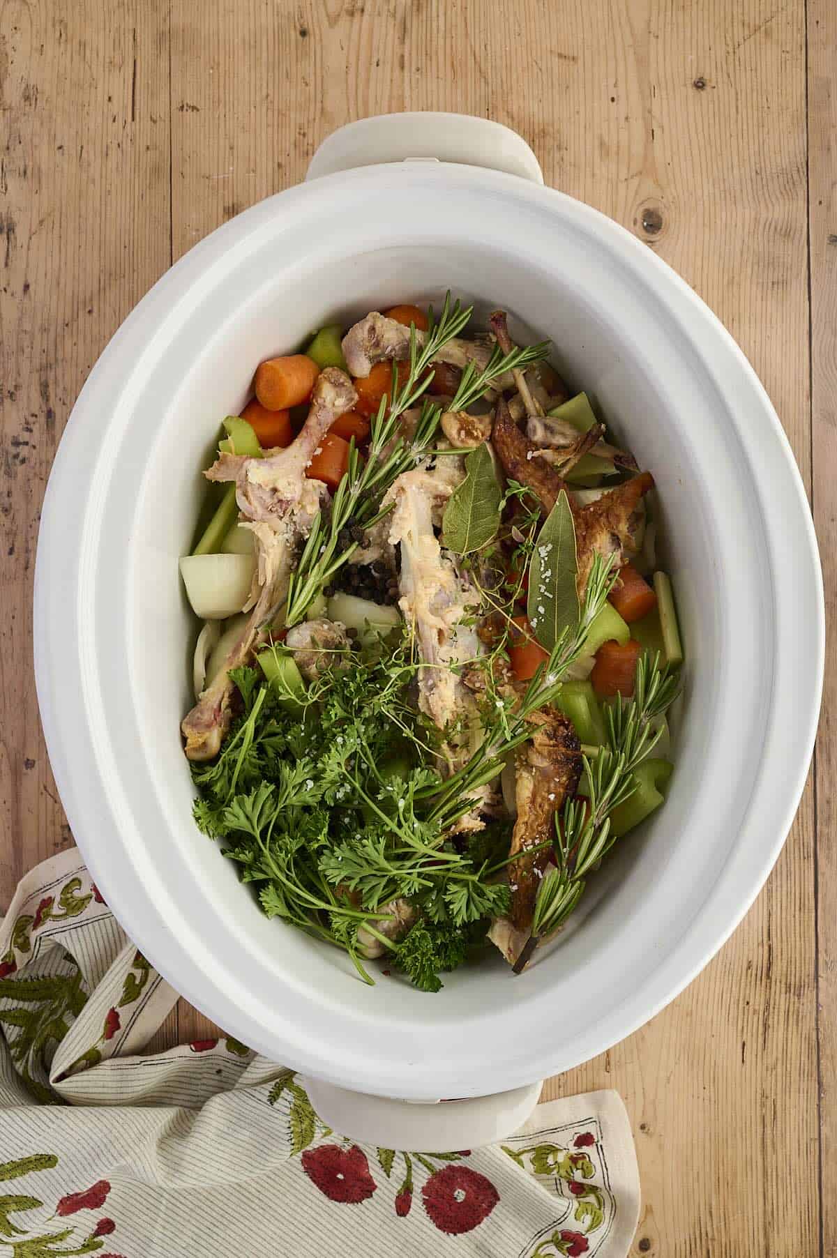 Chicken stock simmering in a crockpot with fresh herbs.