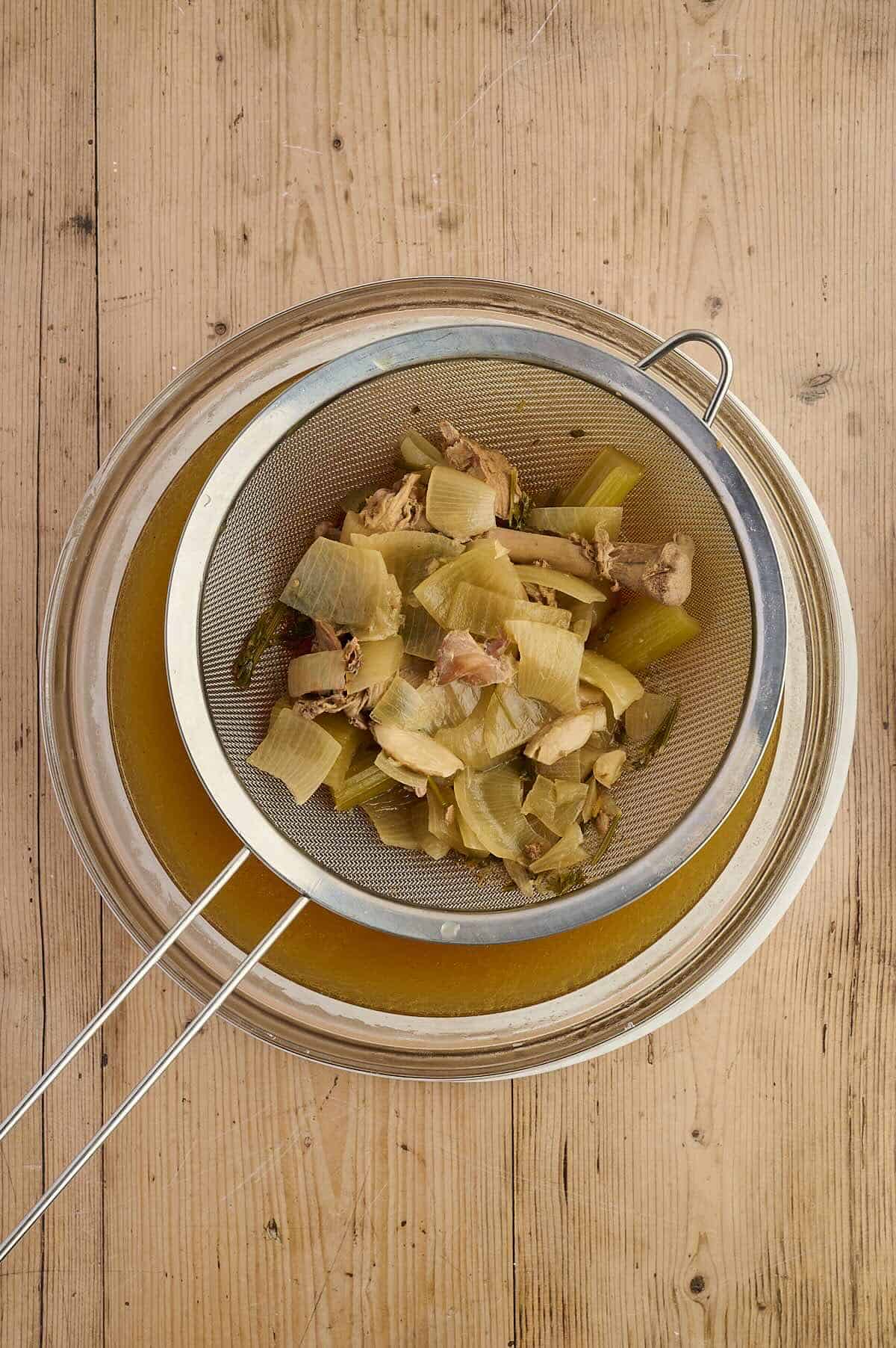 Straining the liquids from the solids for chicken broth.