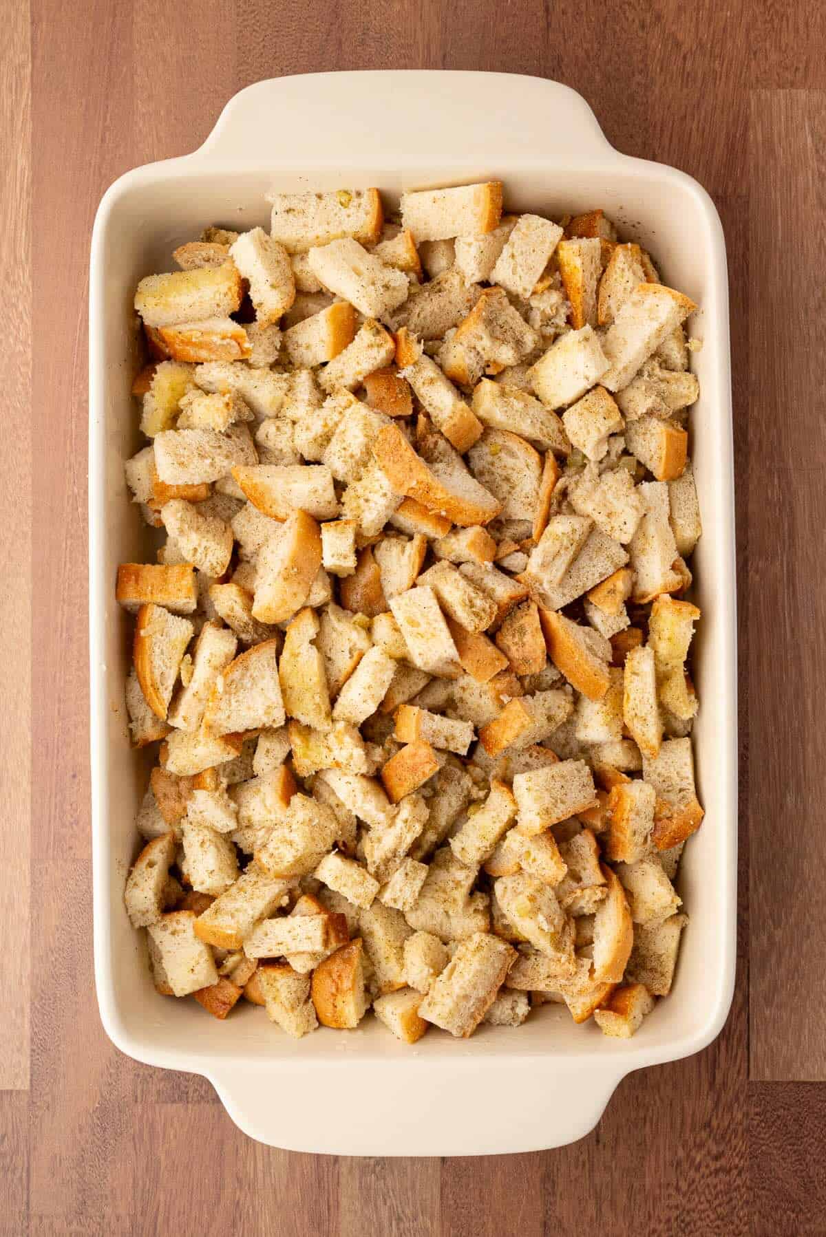 Stuffing mixture spread in a casserole dish before covering with aluminum foil to bake.