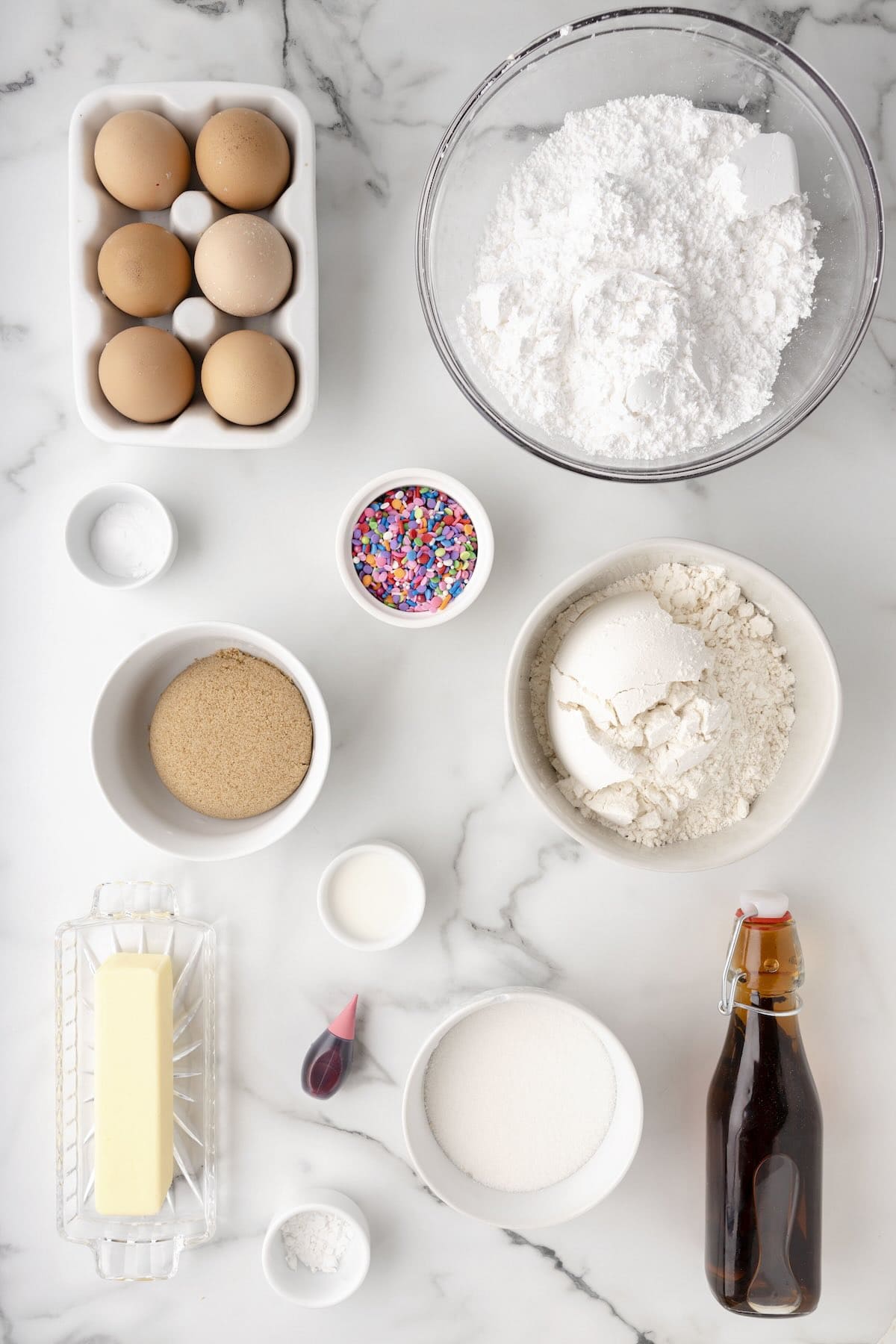 Overhead photo of ingredients for sugar cookie bars including butter, flour, sugar, eggs, and vanilla.