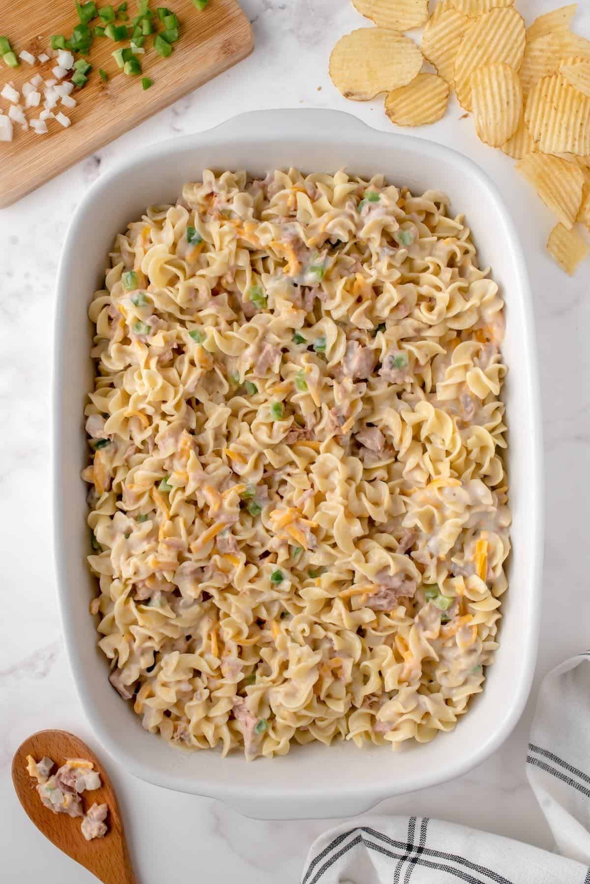 Tuna noodle casserole mixture spread evenly in a 9x13-inch dish before baking.