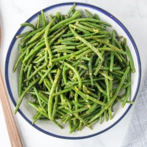 A bowl of cooked green beans fresh from the air fryer, garnished with lemon zest.
