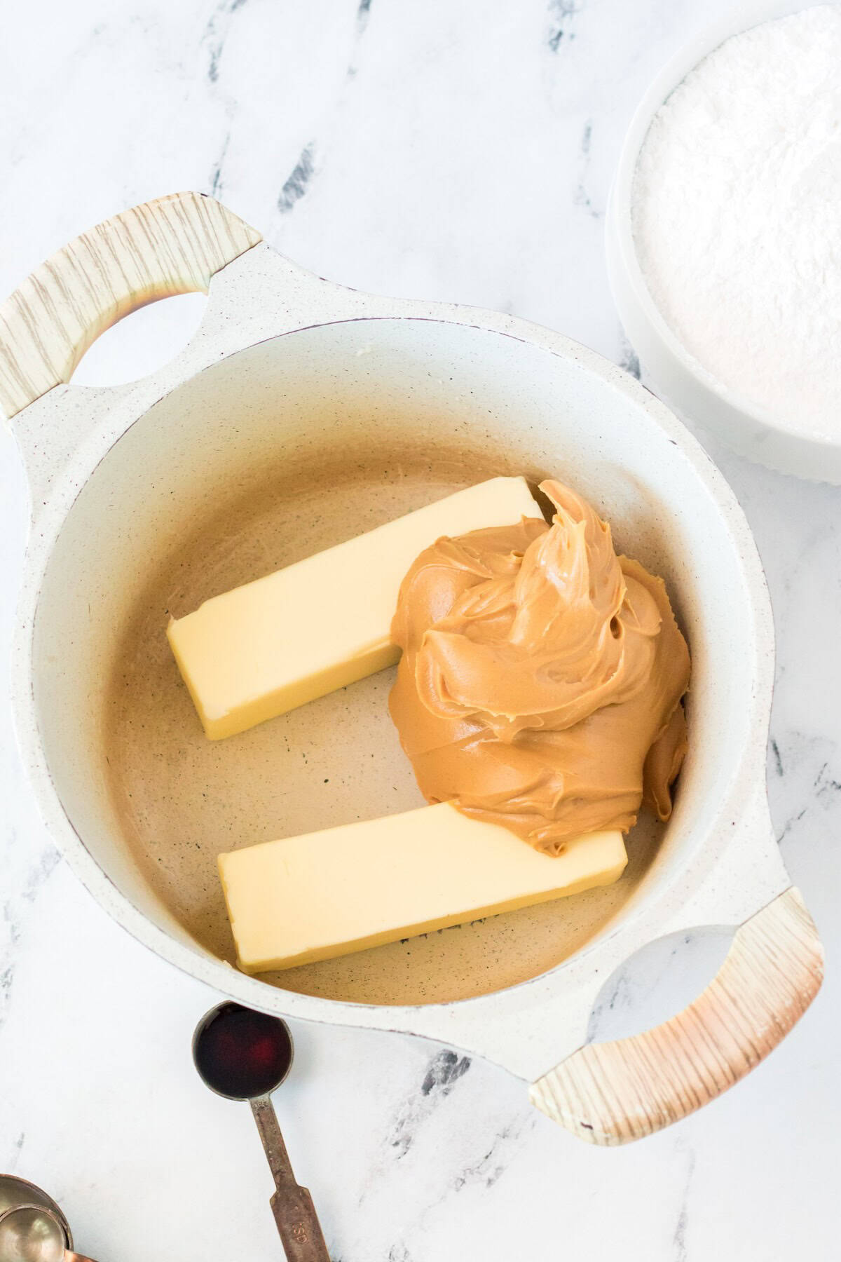 Unmelted butter and peanut butter in a microwave-safe bowl, ready to melt for peanut butter fudge.