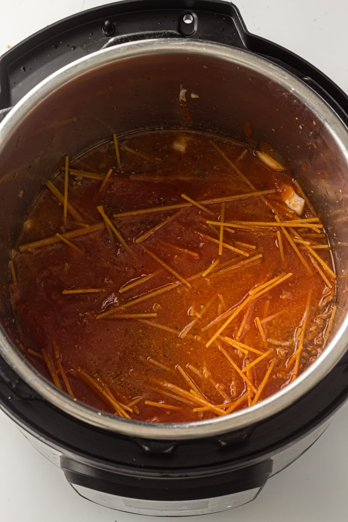 Jarred marinara sauce added to uncooked spaghetti noodles in the Instant Pot