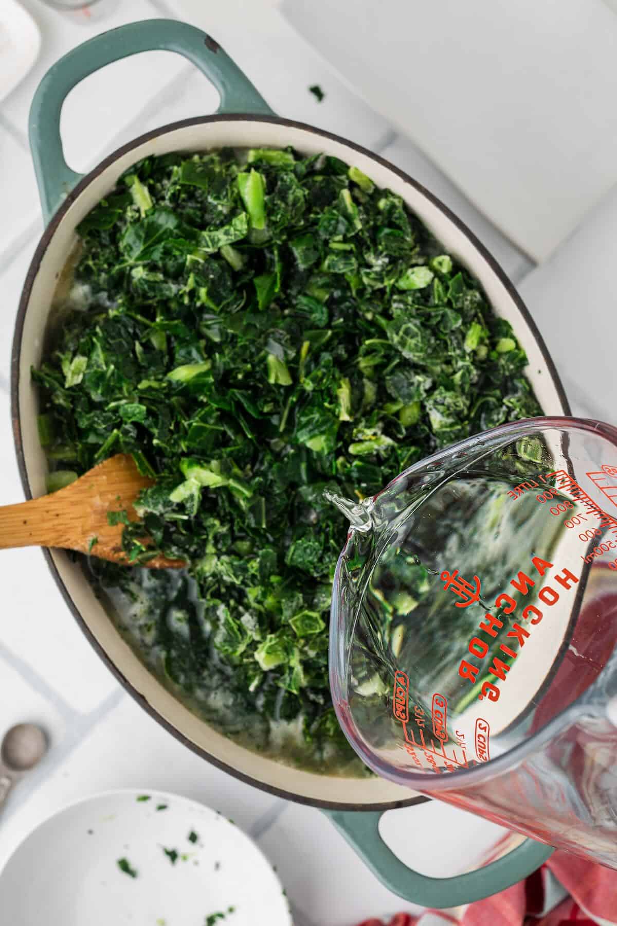 Water being poured over frozen collard greens to cover them before simmering.