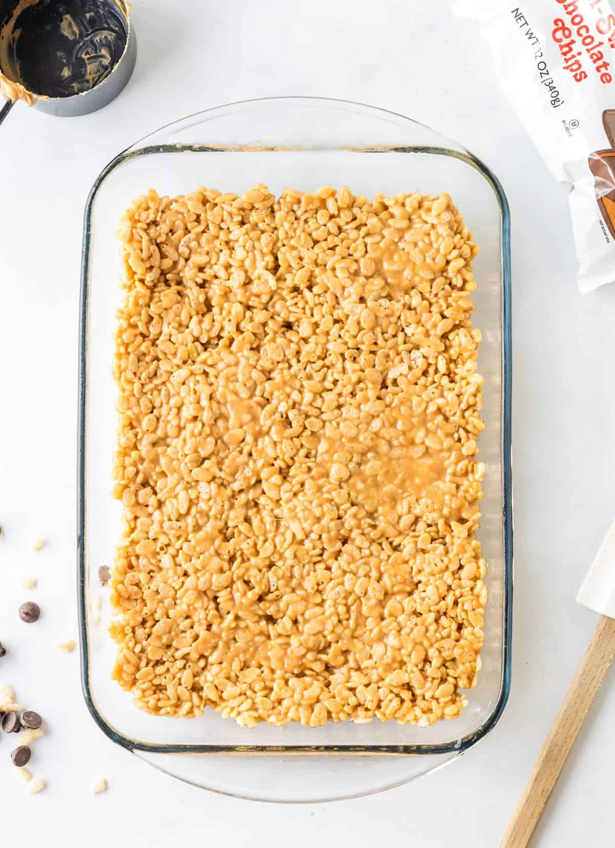 Scotcharoo mixture gently and evenly pressed into 9x13 pan with spatula to form base layer.