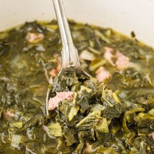 Fully cooked southern-style collard greens with ham hock pieces and flavorful broth.