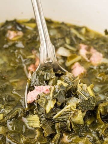 Fully cooked southern-style collard greens with ham hock pieces and flavorful broth.