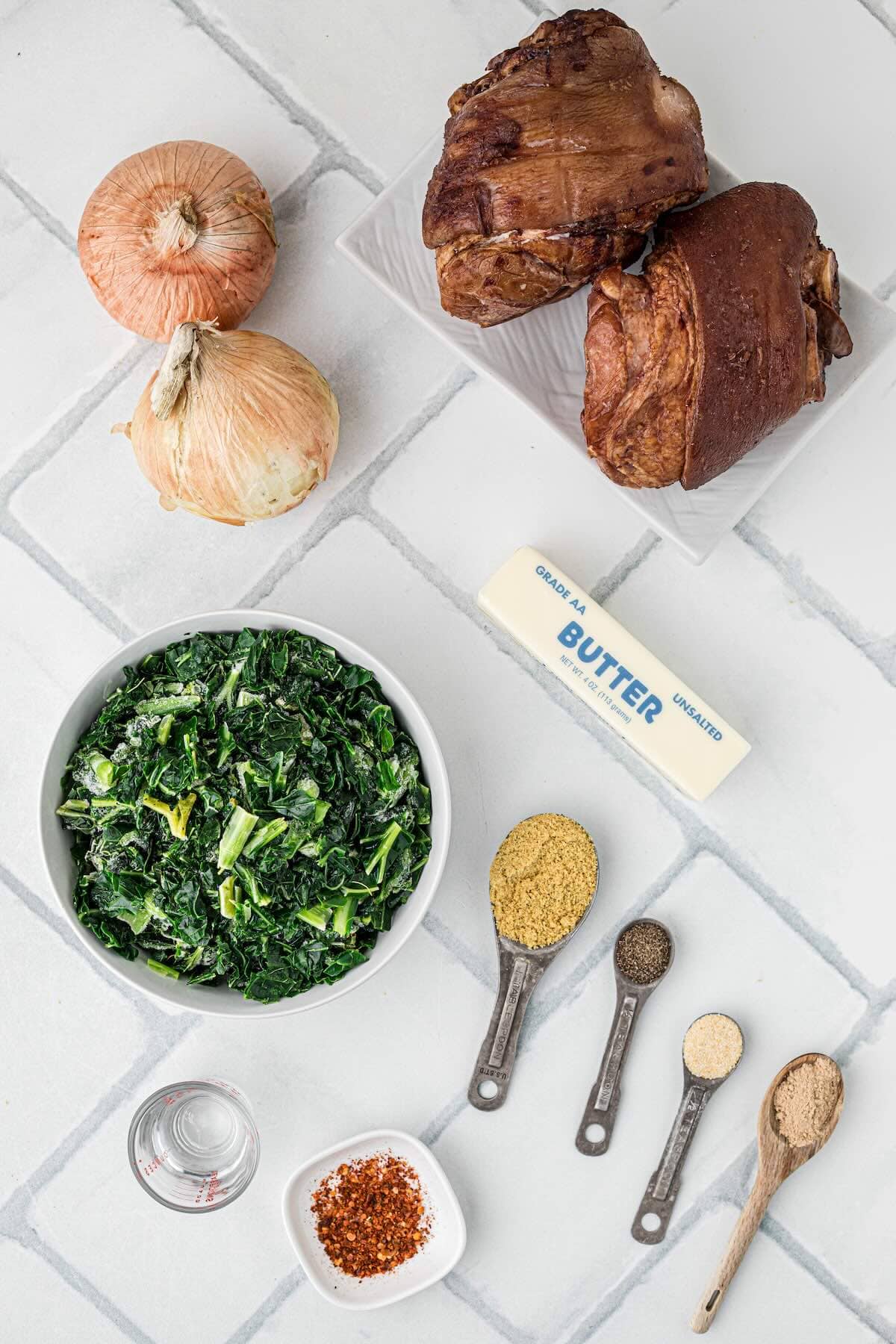 Ingredients to make collard greens using frozen greens, butter, ham hocks, onions, vinegar and spices.