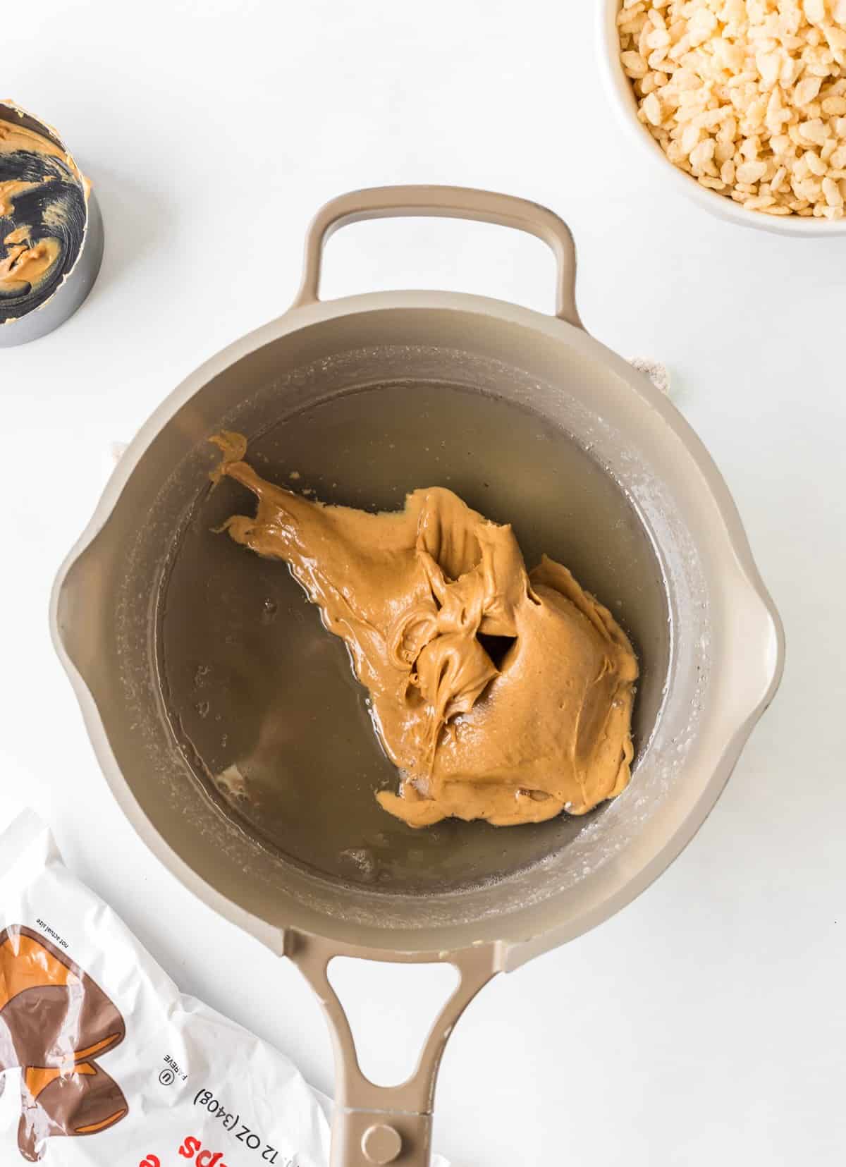 Melting peanut butter into warm corn syrup for soft and chewy scotcharoo bars