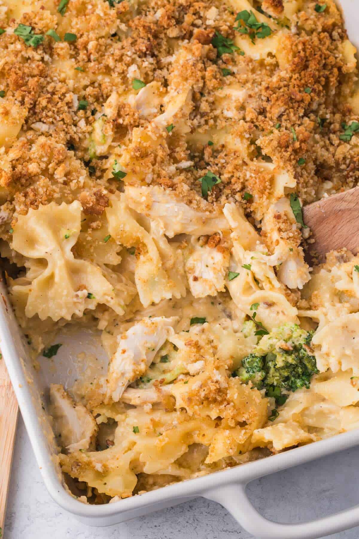 A rectangle casserole dish with scooped out portion of a pasta bake with chicken and broccoli.