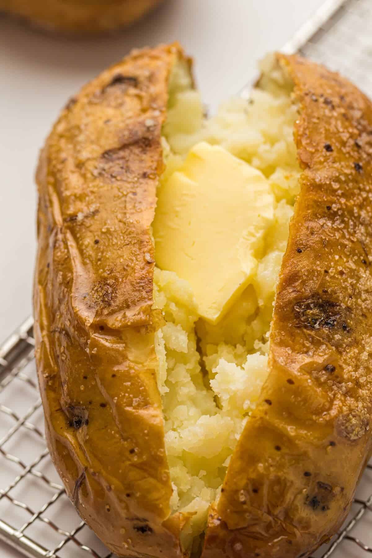 A fluffy baked potato with a pat of butter nestled in it.