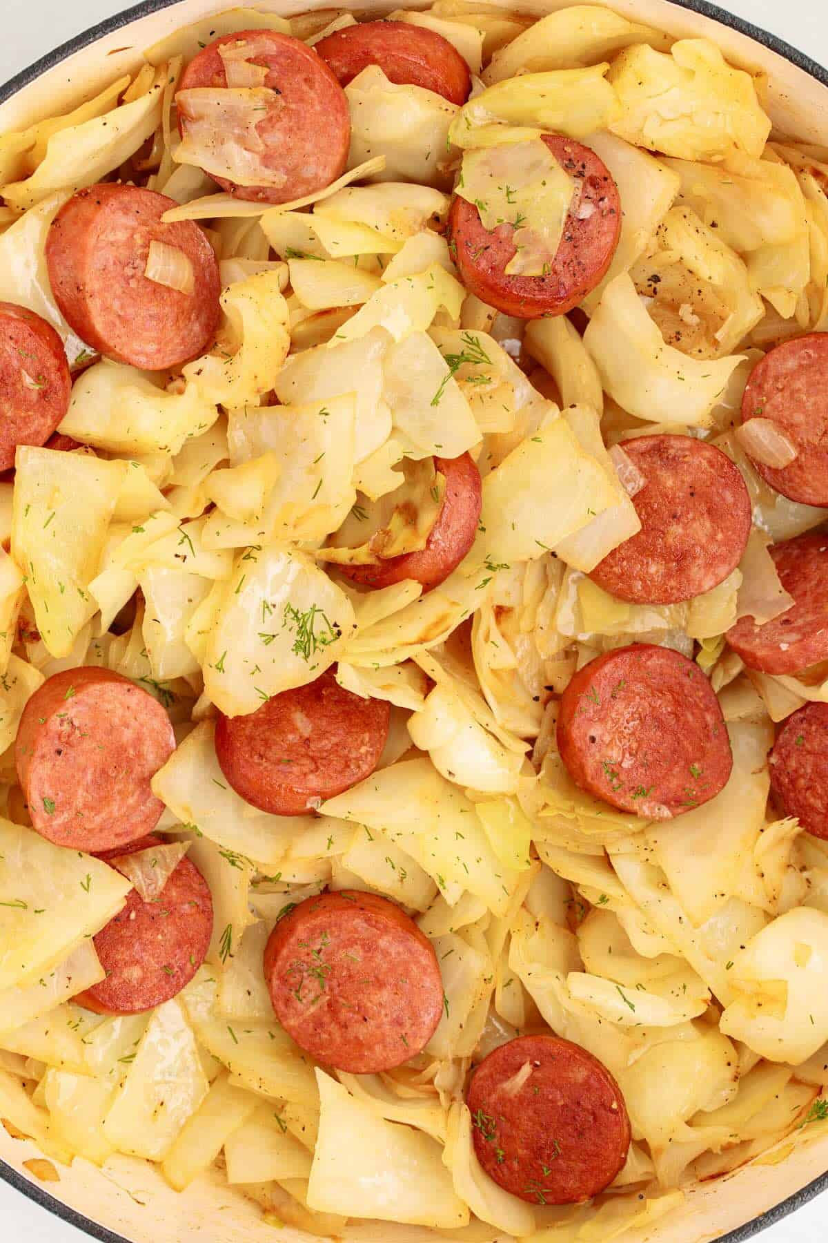 Smoky kielbasa and tender cabbage cooked in a skillet.