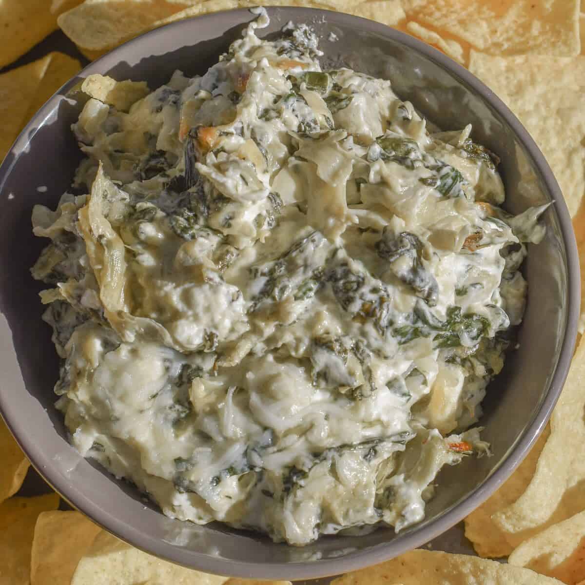 A bowl of gooey and cheesy spinach dip made with jarred artichokes and sautéed fresh spinach.