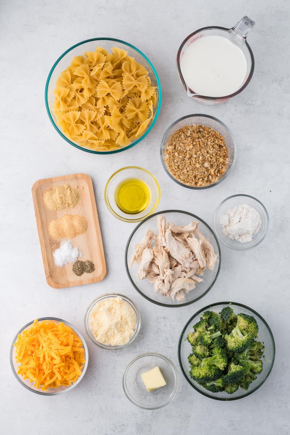 Ingredients to make a chicken broccoli casserole with pasta and cheese sauce ingredients on a countertop.