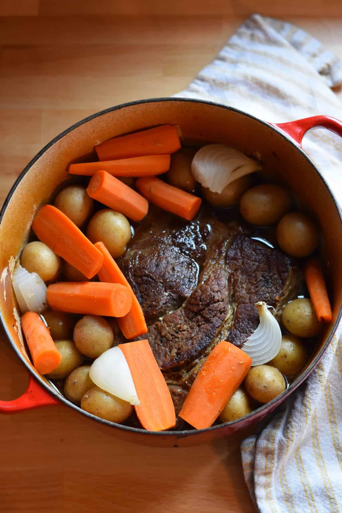 The finished pot roast in a Dutch oven with tender carrots, potatoes and onions, ready to remove to a platter and shred.