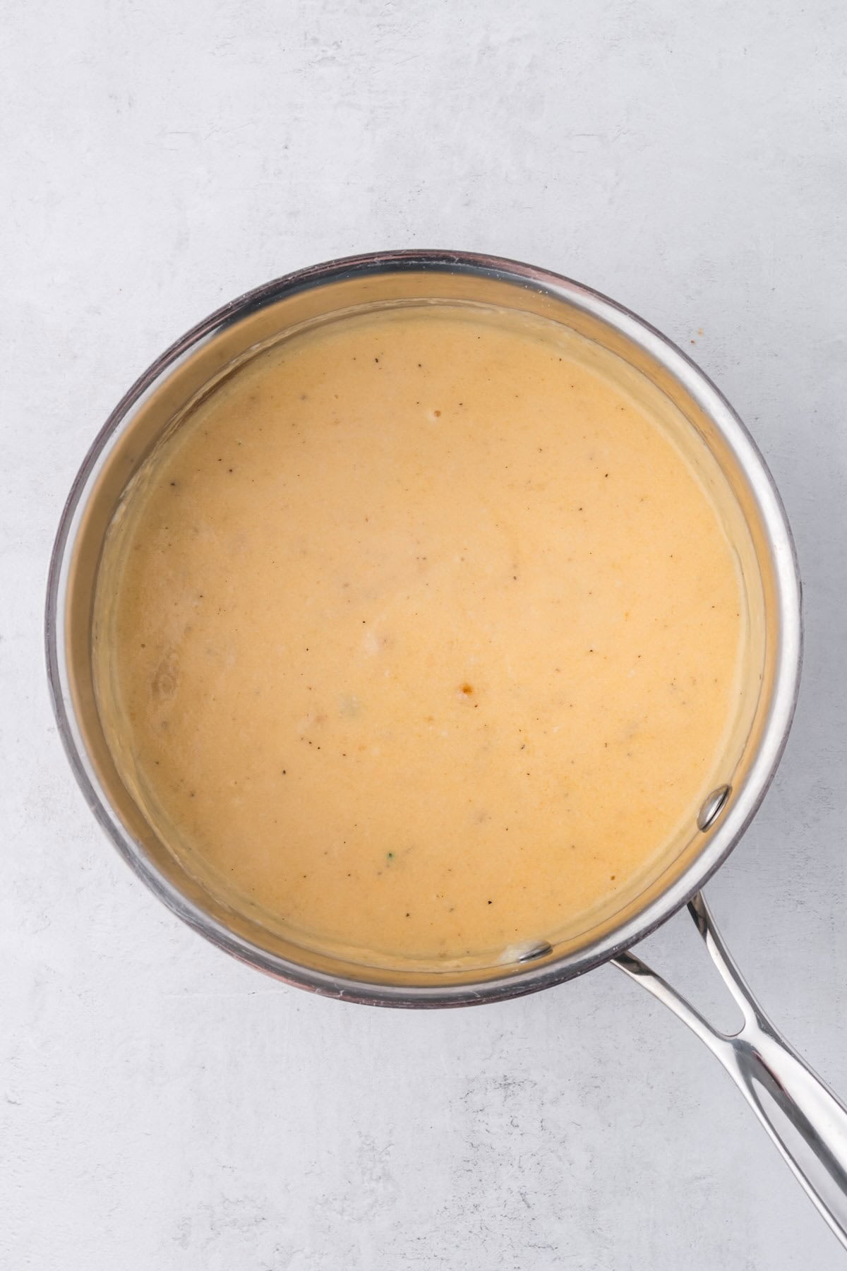 A pan of homemade cheese sauce with milk and cheeses.