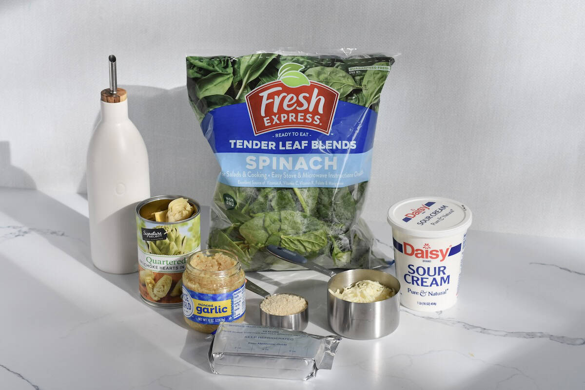 Ingredients for spinach artichoke dip with fresh spinach, artichokes, and cheese.