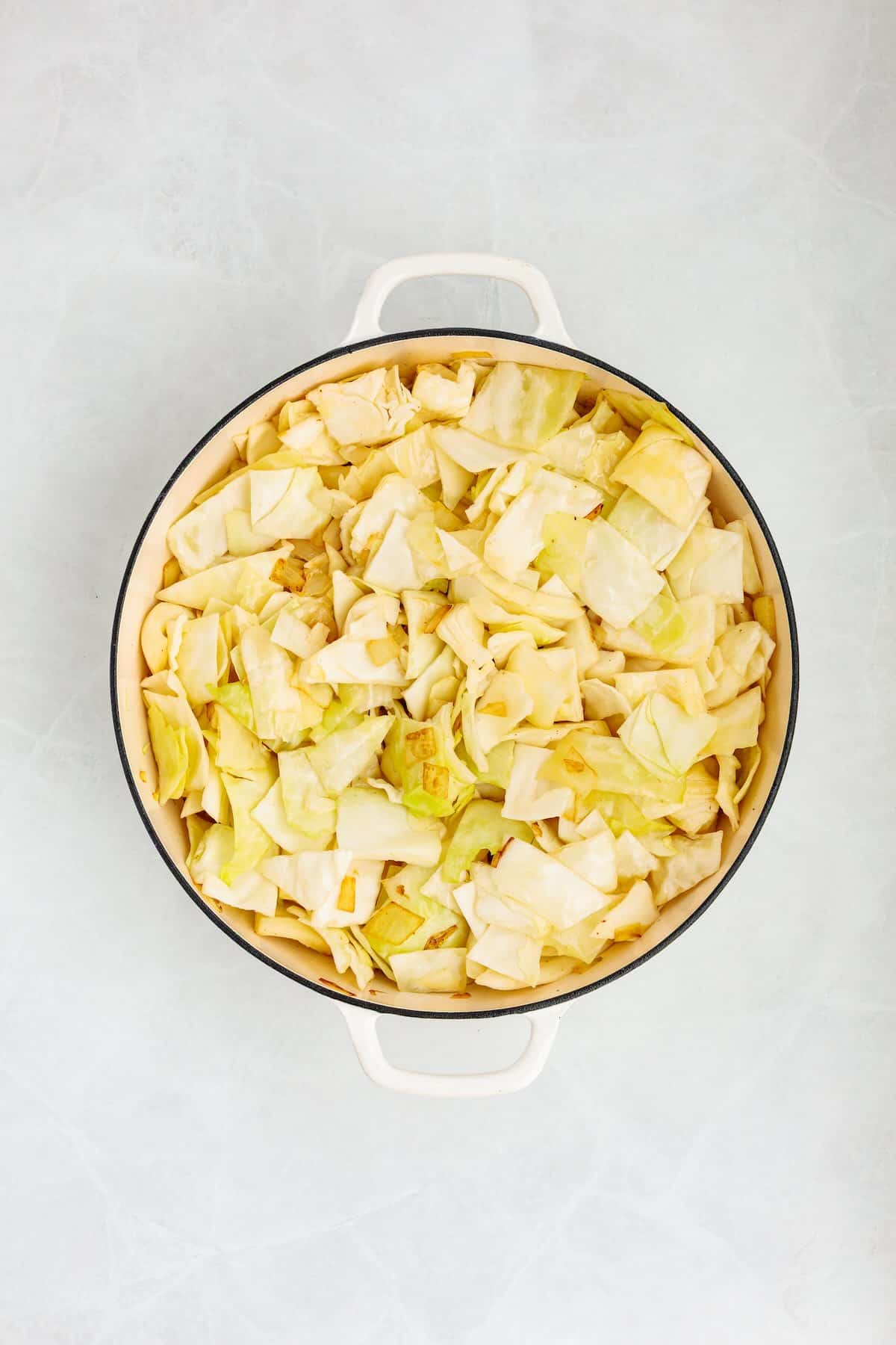 Chopped green cabbage heaped in a hot skillet.