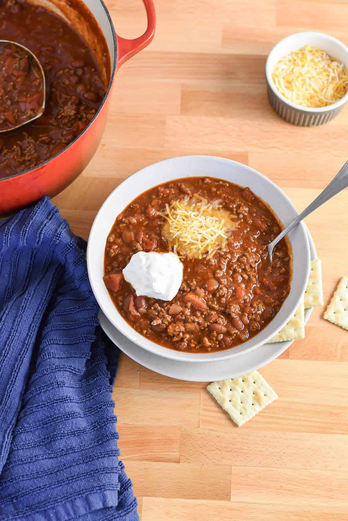 Bowl of classic chili for a crowd topped with shredded cheese and sour cream.