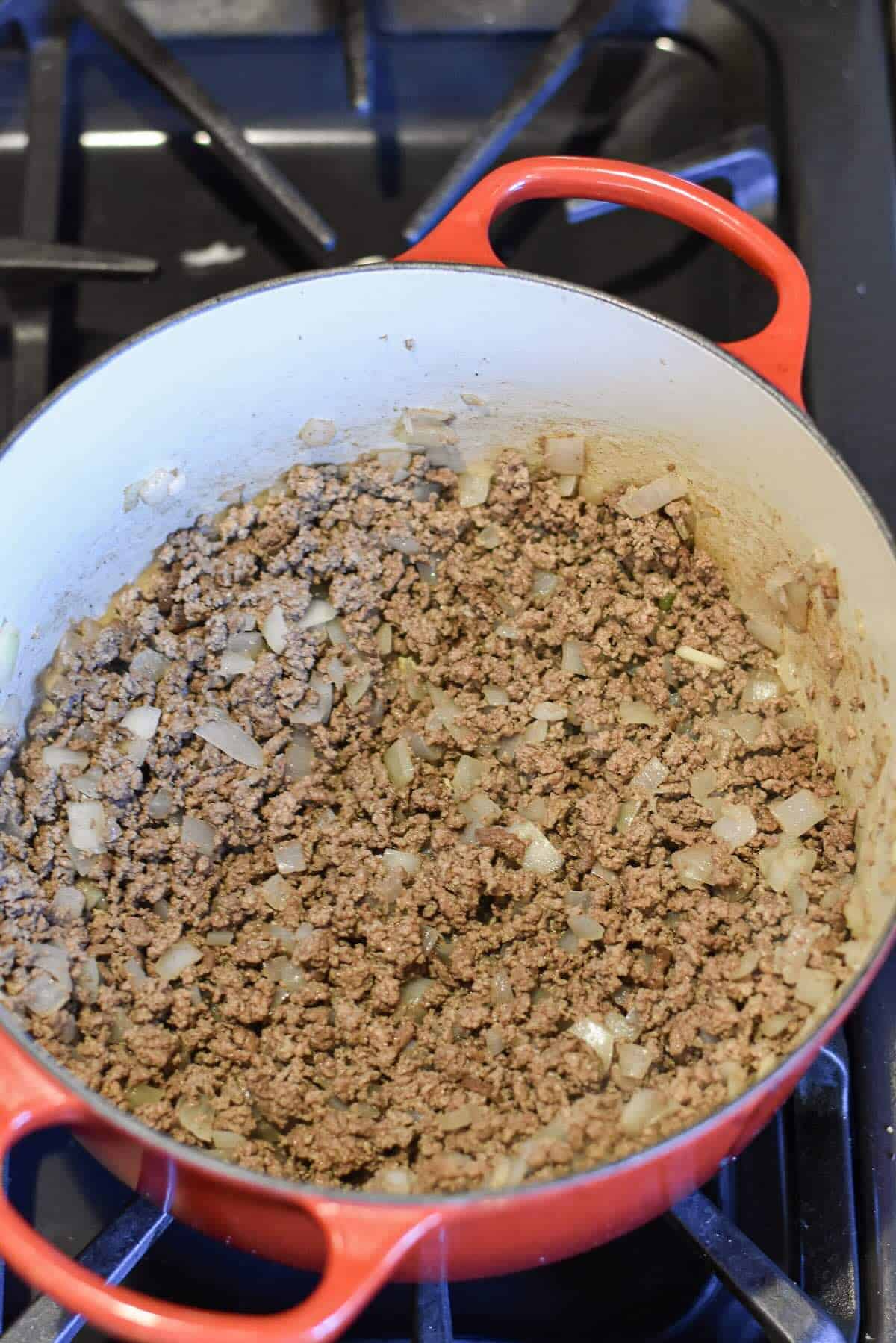 Ground beef and onions browning in a Dutch oven for chili.