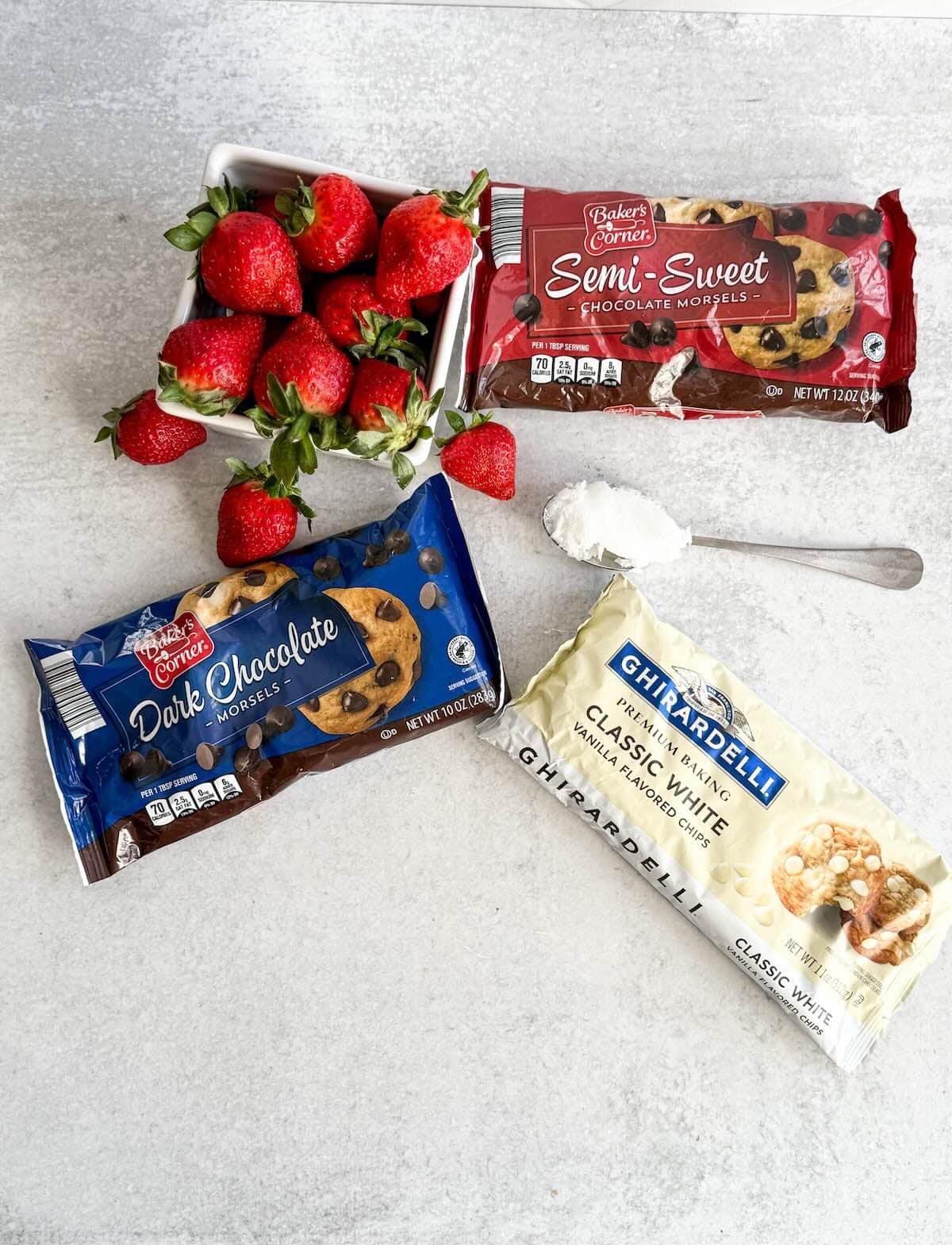 Ingredients for making chocolate covered strawberries including fresh strawberries, dark chocolate, semi-sweet chocolate, white chocolate, and coconut oil
