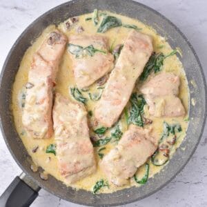 Flaky and tender salmon in a rich creamy sauce with spinach, in a skillet and ready to serve.