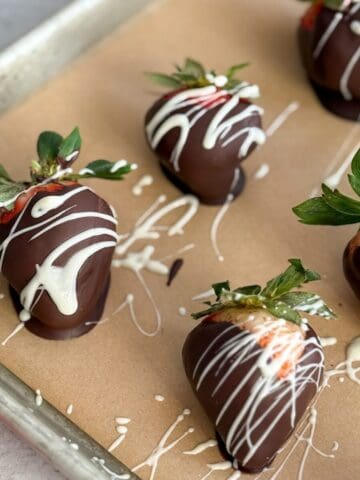 Parchment covered baking sheet topped with chocolate covered strawberries.