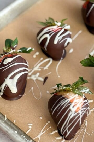 Parchment covered baking sheet topped with chocolate covered strawberries.
