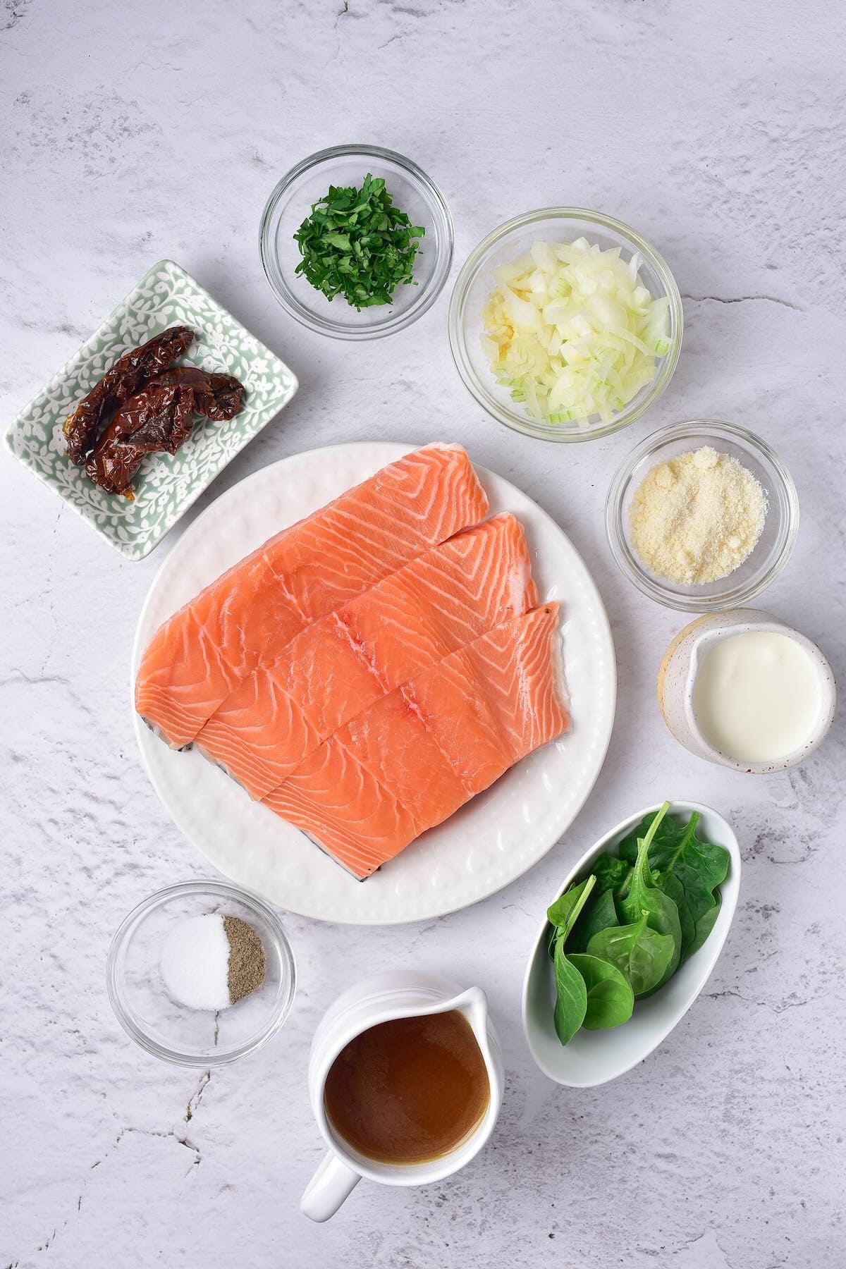 Ingredients for Tuscan salmon including salmon, spinach, sun-dried tomatoes, cream, garlic, and parmesan.