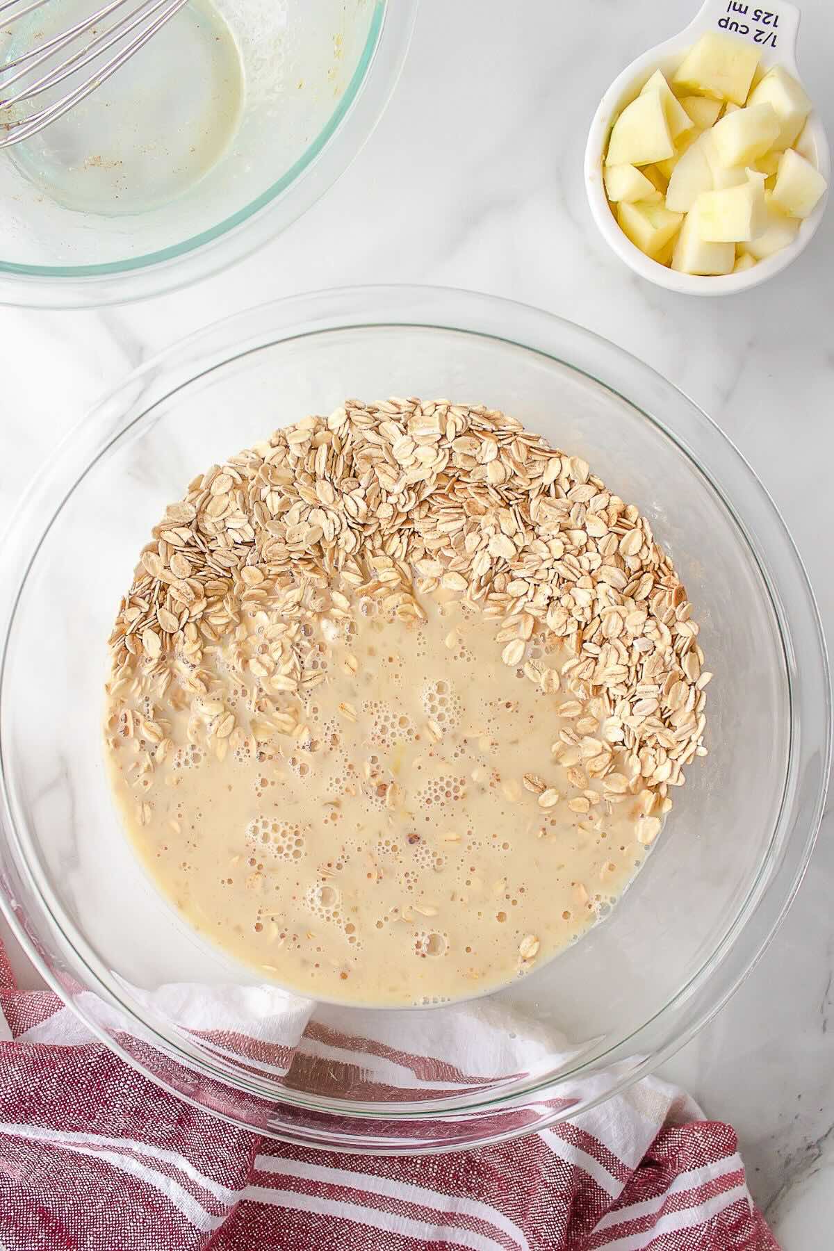Adding rolled oats and cinnamon to apple baked oatmeal mixture.