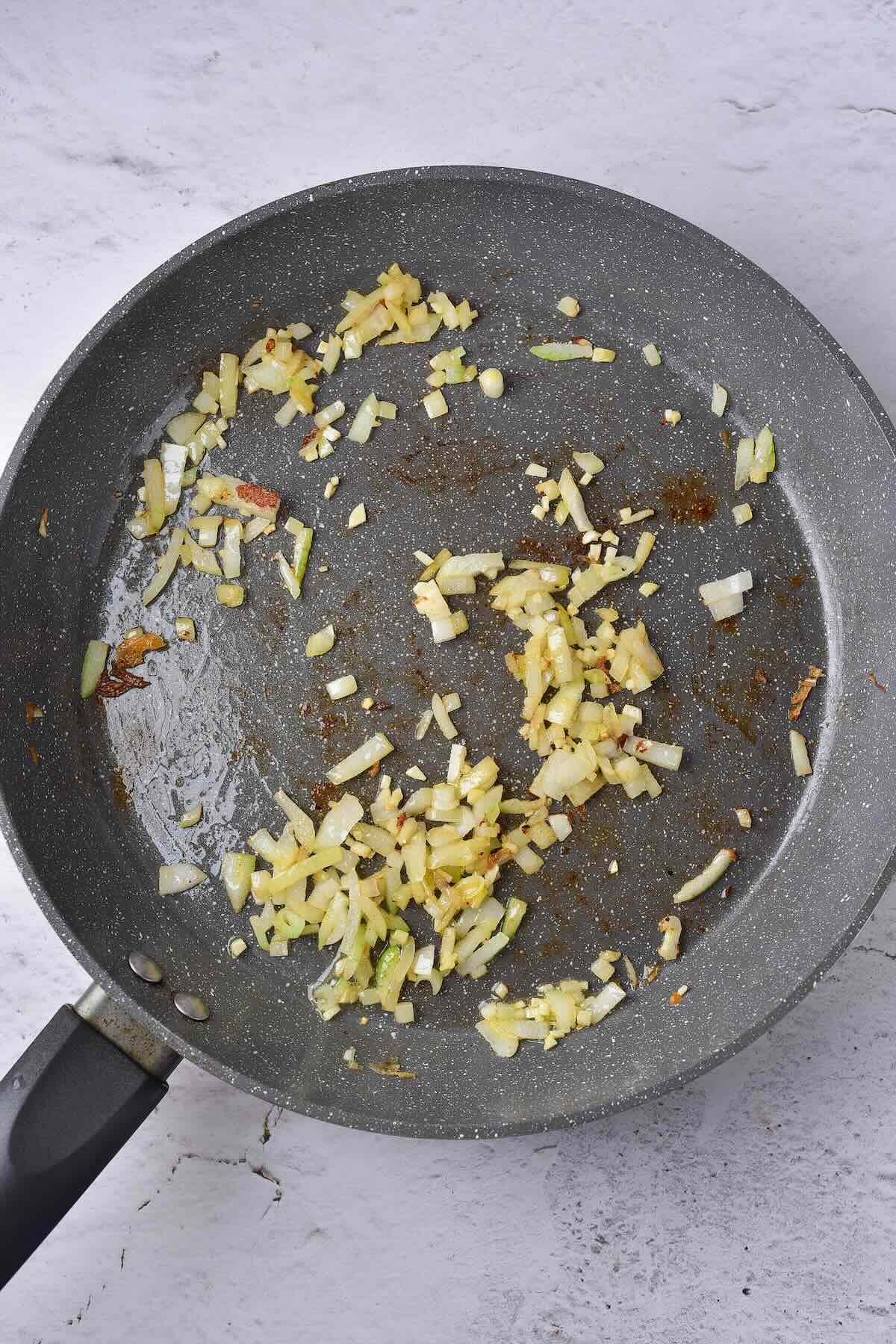 Onions and garlic cooking in a skillet as a base to make a cream sauce for salmon.