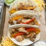 Three flour tortillas filled with chicken, bell peppers and onions.