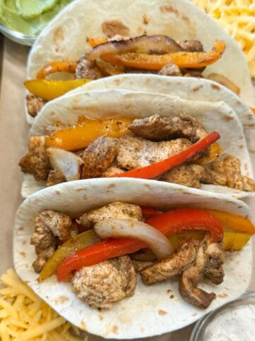 Three flour tortillas filled with chicken, bell peppers and onions.