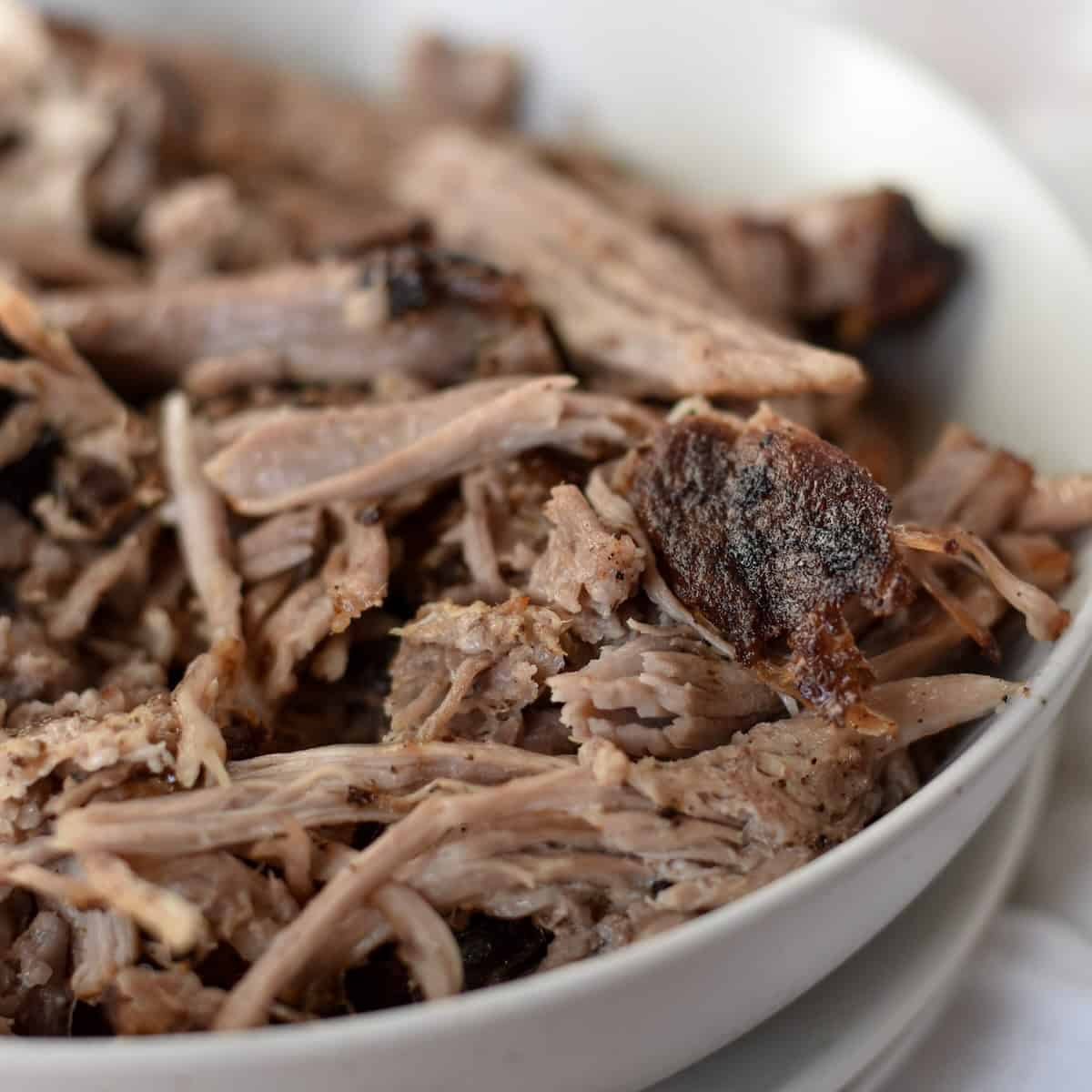 Juicy shredded air fryer pulled pork in a bowl ready for topping with bbq sauce.
