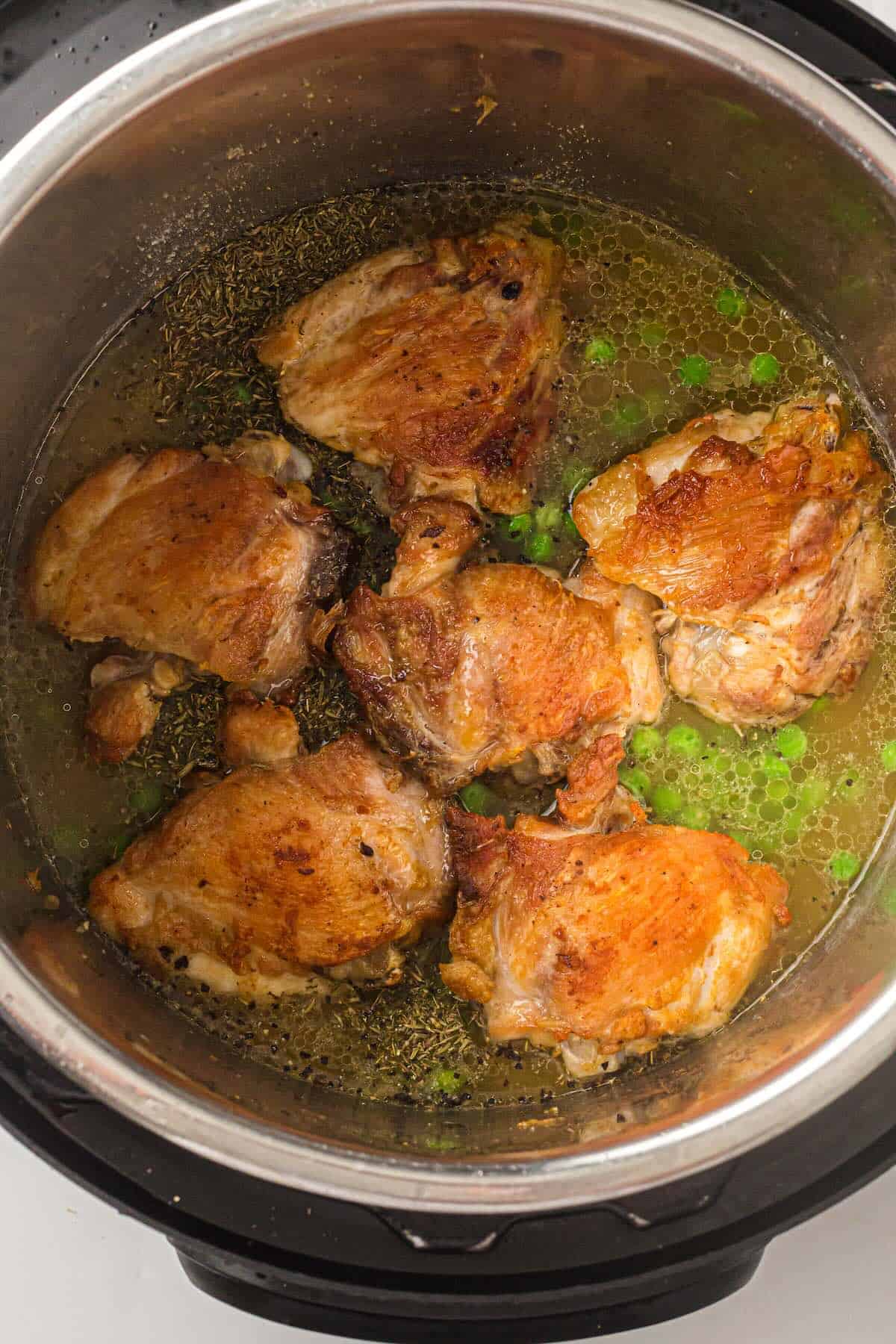 Chicken thighs placed on top of rice in the Instant Pot before pressure cooking.