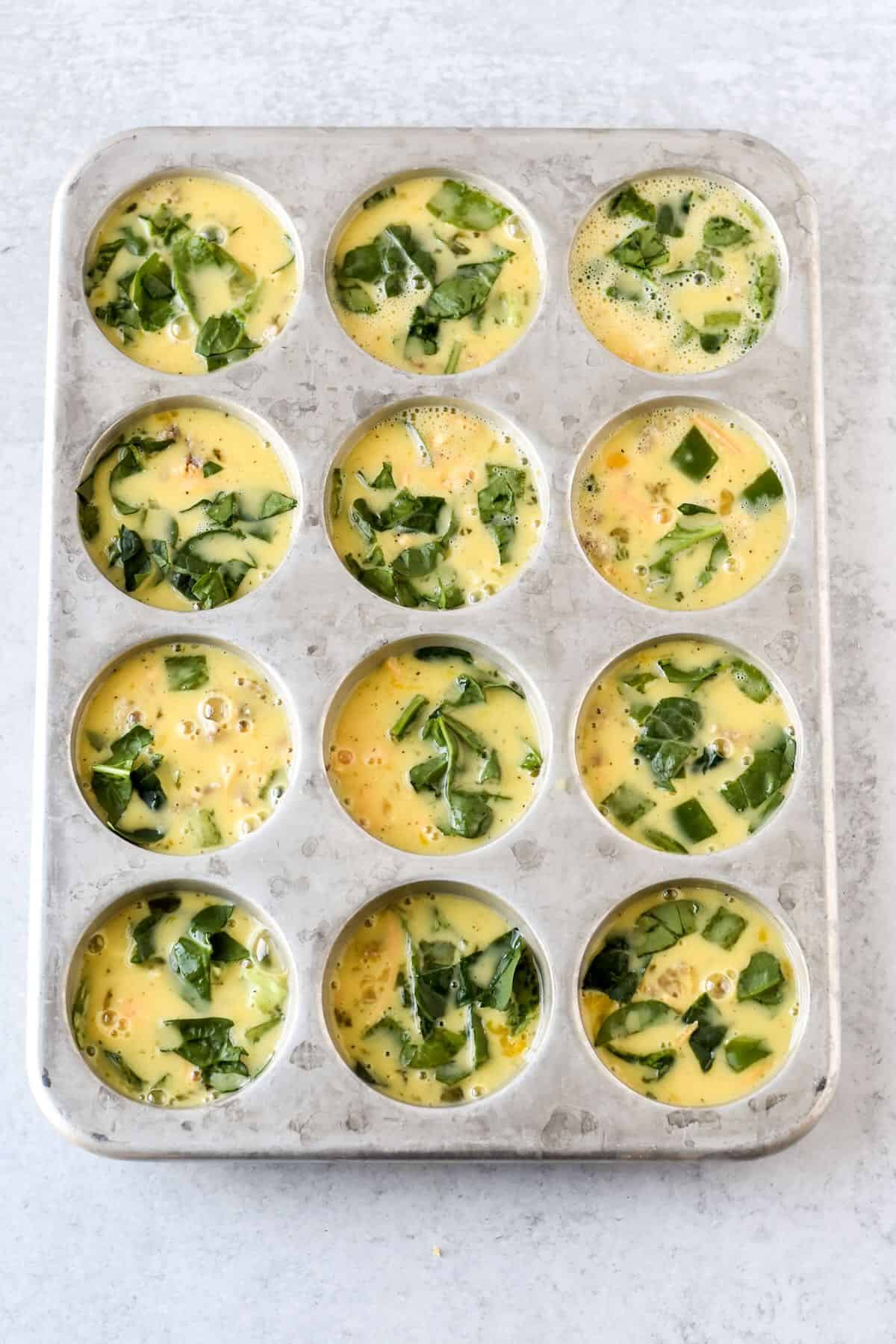 Egg mixture poured into muffin tin for mini crustless quiche.