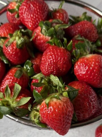 A bunch of strawberries ready to be rinsed, hulled and frozen.