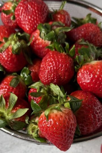 A bunch of strawberries ready to be rinsed, hulled and frozen.