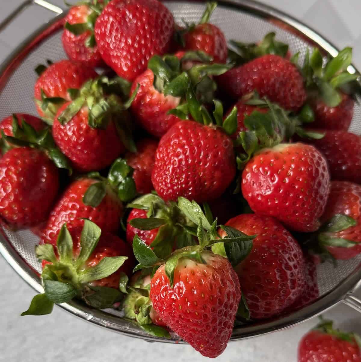 A bunch of strawberries ready to be rinsed, hulled and frozen.