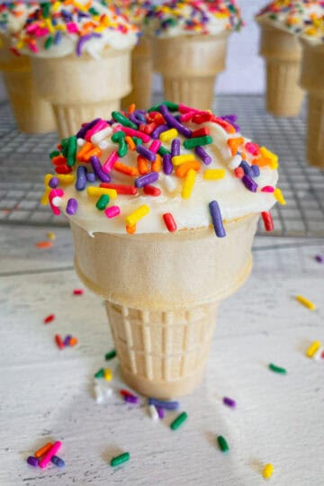 A cupcake made in an ice cream cone using cake mix and topped with frosting and sprinkles.