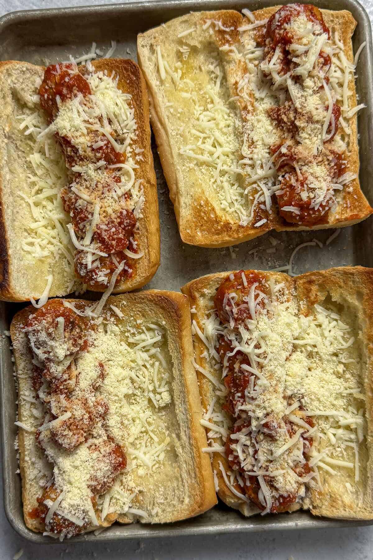 Shredded mozzarella cheese added on top of meatball subs before baking.