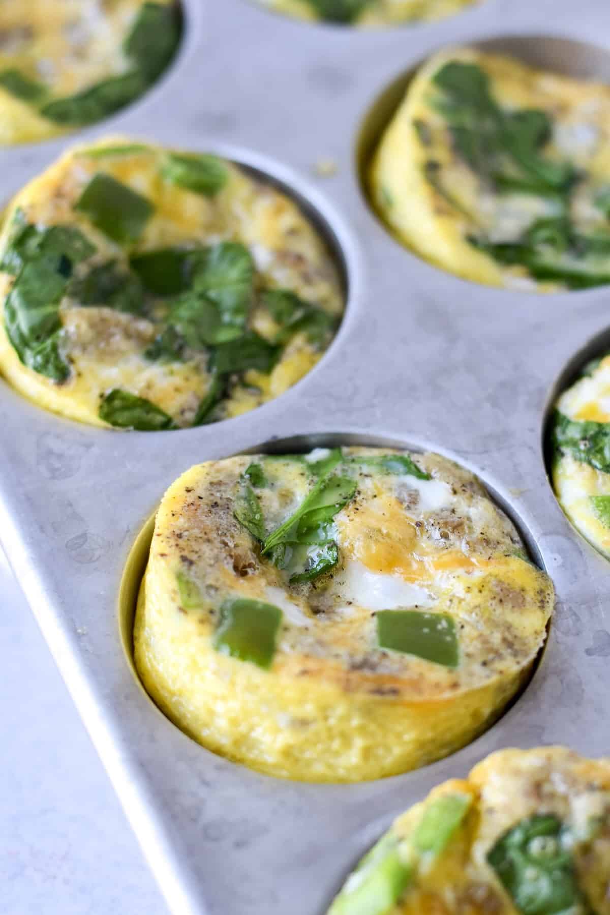 Mini crustless quiche baked in a muffin pan with sausage spinach and cheddar.
