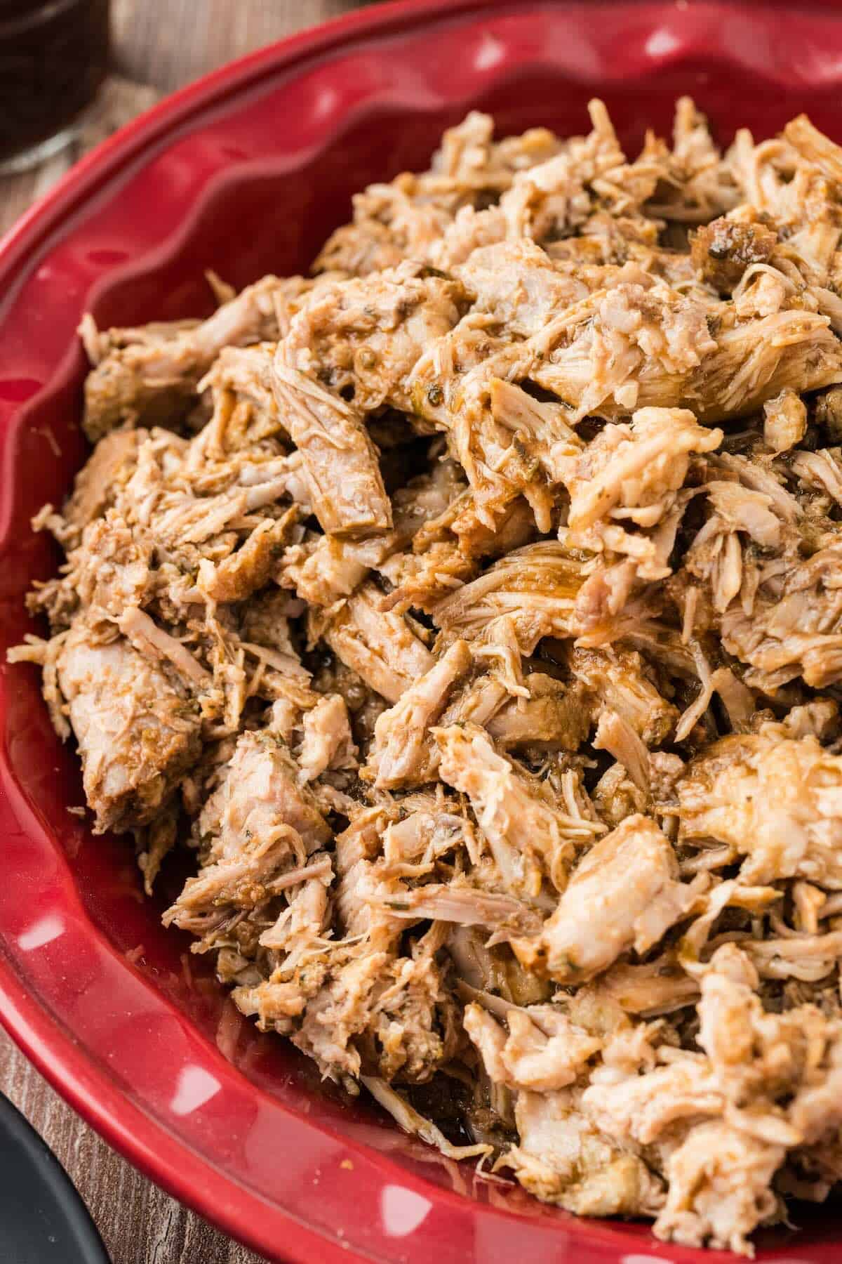 A red pie plate filled to the rim with juicy shredded pork.