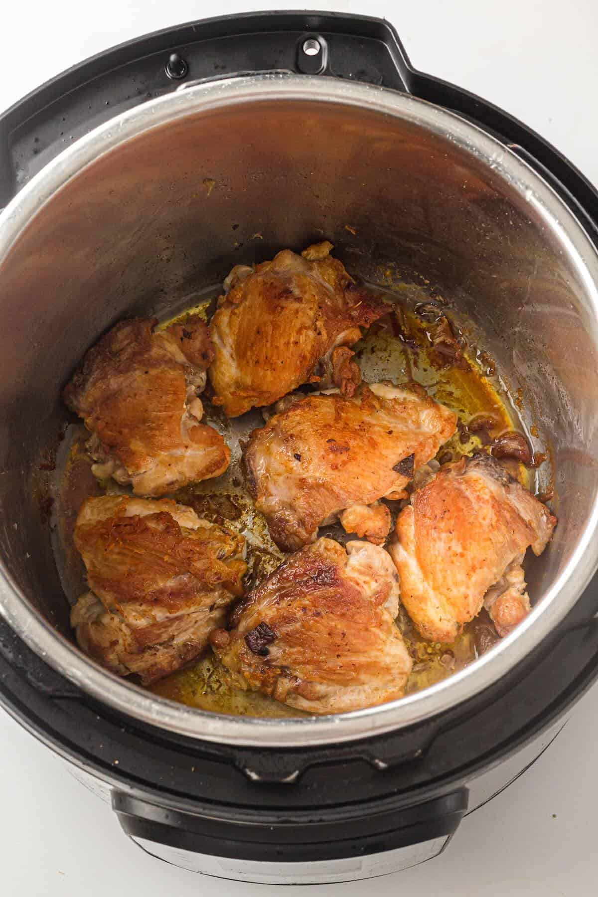 Searing chicken thighs in the Instant Pot before cooking chicken and rice.